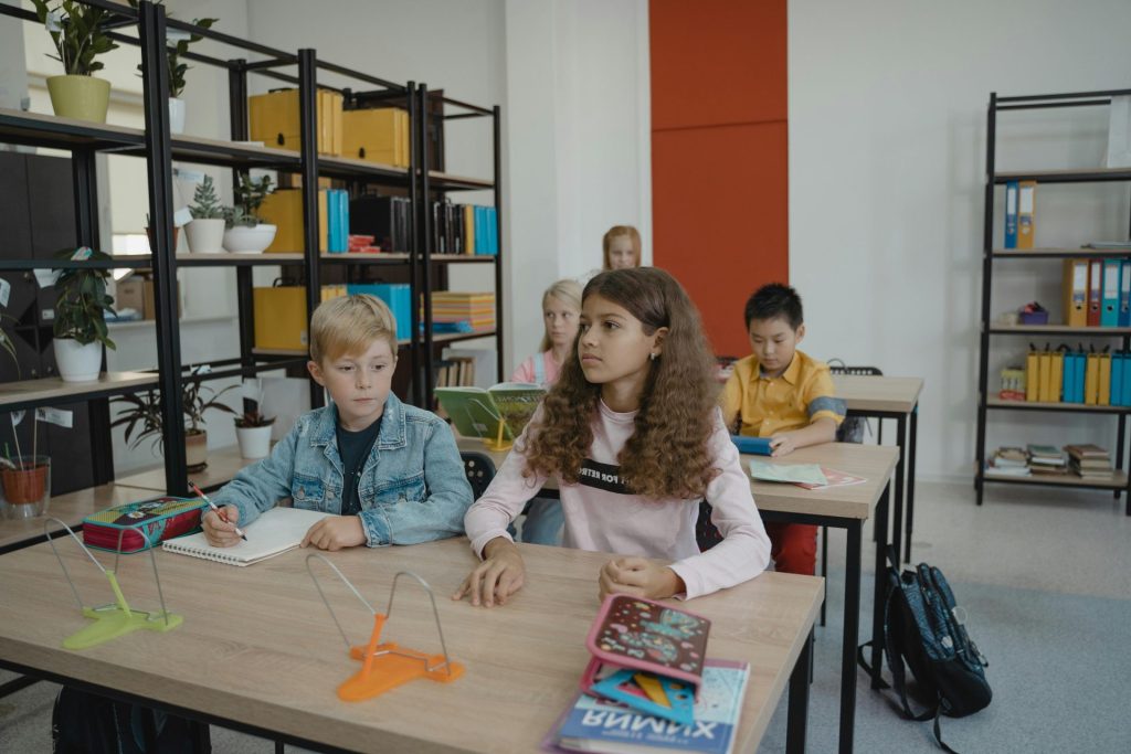 Students engaging in classroom learning at desks with books and notebooks.